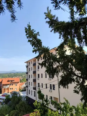 a tall white building with trees in the foreground at Moj kutak Sokobanja in Soko Banja