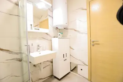 a white bathroom with a sink and a mirror at Apartman NN in Vrnjci