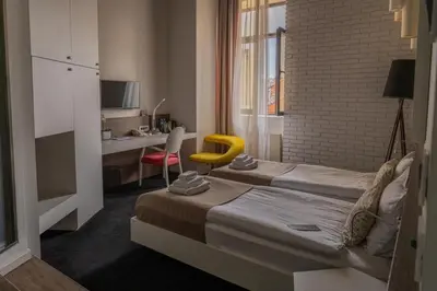 a hotel room with two beds and a yellow chair at Garni Hotel Eter in Niš