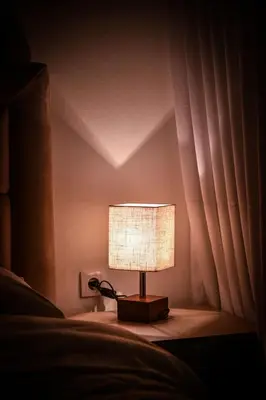 a lamp sitting on a table next to a bed at Apartmani EMA SL in Vranje