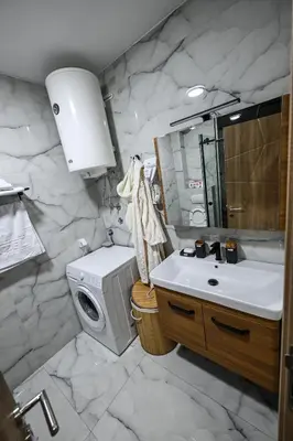 a bathroom with a sink and a washing machine at Apartmani EMA SL in Vranje
