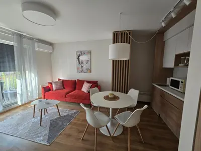 a living room with a red couch and a table and chairs at Sunny lux apartman II in Vrnjačka Banja