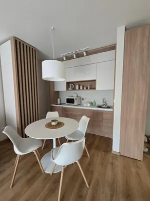 a dining room with a table and chairs and a kitchen at Sunny lux apartman II in Vrnjačka Banja