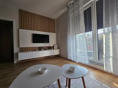 a living room with two tables and a tv at Sunny lux apartman II in Vrnjačka Banja