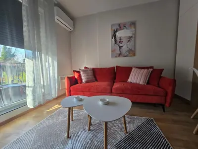 a living room with a red couch and two tables at Sunny lux apartman II in Vrnjačka Banja