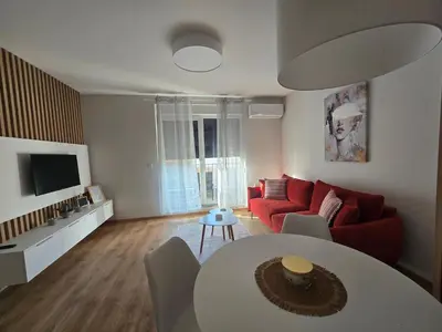 a living room with a red couch and a table at Sunny lux apartman II in Vrnjačka Banja
