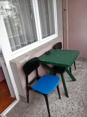 a green table and a blue chair next to a window at Apartman Klinički Centar Niš in Niš
