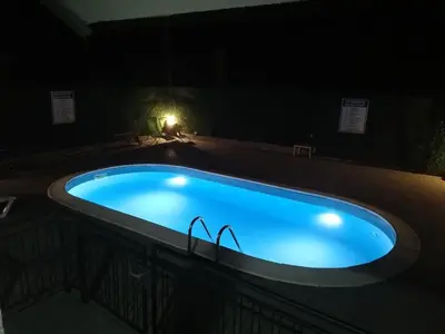 a swimming pool at night with two glasses in it at Royal 019 in Vrnjačka Banja
