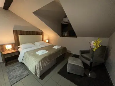 a bedroom with a large bed and a chair at JP Motel Mali Pariz in Bor