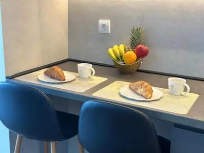 a table with two plates of croissants and a bowl of fruit at The Daily Nest in Niš
