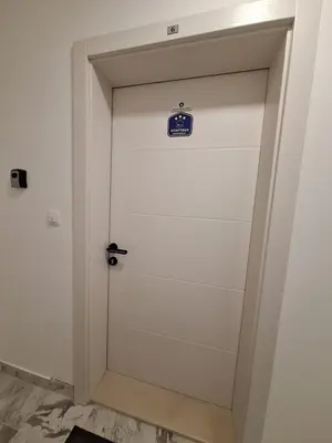 a white door with a blue sign on it at Apartman MILOVANOVIĆ in Vrnjačka Banja