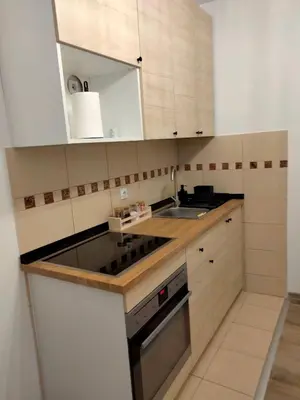 a small kitchen with white cabinets and a sink at Apartman Nada in Jagodina