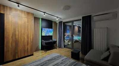a room with a bedroom with a desk and a couch at Delta Planet Apartman in Niš