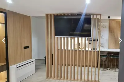 a living room with a tv and a wooden partition at Apartman La Casa and Spa in Vranje