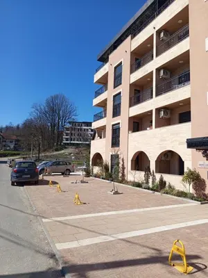 a parking lot with yellow barriers in front of a building at Ramonda apartman sa bazenom, Vrnjačka Banja in Vrnjačka Banja