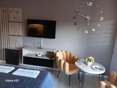 a living room with a table and a clock on the wall at Apartman 018 in Soko Banja