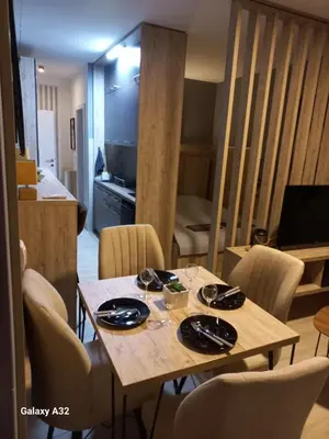 a dining room table with chairs and a kitchen in the background at Apartman 018 in Soko Banja