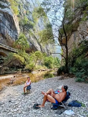 a man sitting in a chair next to a river at Vila Dika in Poganovo