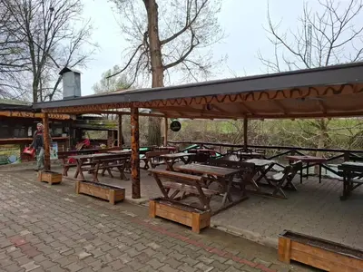 a group of picnic tables and benches with a roof at Viking apartaments in Niš