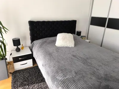 a bedroom with a large bed with a black headboard at Apartman KUM in Vrnjačka Banja