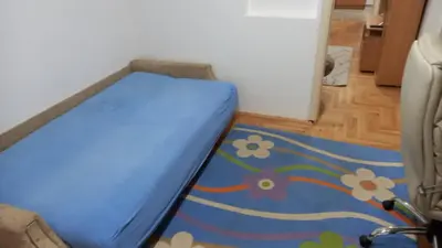 a blue bed in a room with a flower rug at Centar & peace in Niš
