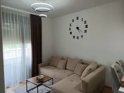 a living room with a couch and a clock on the wall at Apartman Jana in Vrnjačka Banja