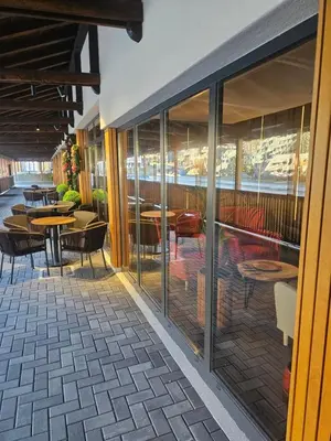 a restaurant with glass doors and tables and chairs at Nest 316 Bela Reka Kopaonik in Brzeće