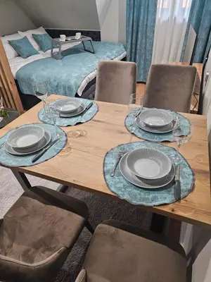 a wooden table with plates and wine glasses on it at Nest 316 Bela Reka Kopaonik in Brzeće