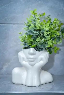a white vase with a green plant in it at Sunčani Horizonti in Soko Banja
