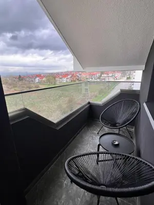 a balcony with two chairs and a table and a large window at Sunčani Horizonti in Soko Banja