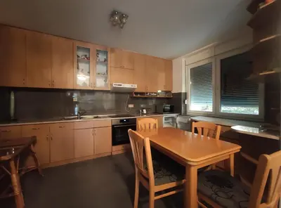 a kitchen with wooden cabinets and a table and chairs at VILA RUŽA - Grand apartman 1 in Soko Banja