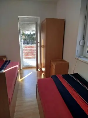a room with two beds and a door to a patio at VILA RUŽA - Grand apartman 1 in Soko Banja