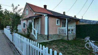a small house with a white fence in front of it at Apartman SIMONA in Bor