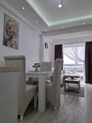 a white dining room with a table and chairs at Apartman Kamelia in Jagodina