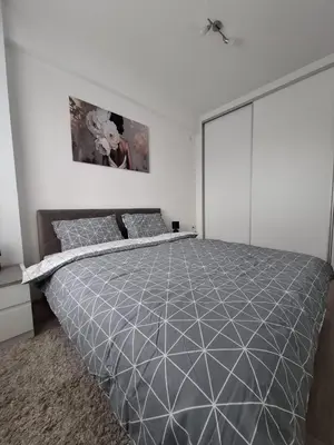 a bedroom with a large bed in a white room at Apartman Kamelia in Jagodina