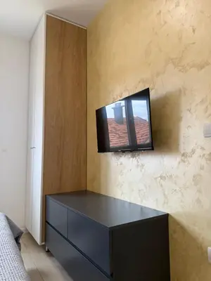 a room with a tv on a wall with a dresser at Cvetkovic apartman in Soko Banja