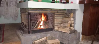 a brick fireplace with a fire in it at Vila Petrov in Lukavica
