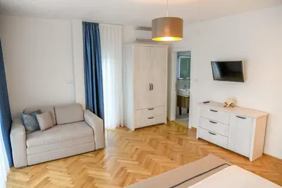 a living room with a white couch and a television at Vila sa bazenom Vrnjačka Idila in Vrnjačka Banja