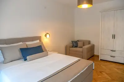 a bedroom with a large bed and a chair at Vila sa bazenom Vrnjačka Idila in Vrnjačka Banja