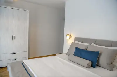 a bedroom with a large white bed with a blue pillow at Vila sa bazenom Vrnjačka Idila in Vrnjačka Banja