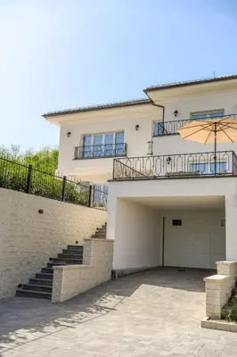 a white house with a staircase and an umbrella at Vila sa bazenom Vrnjačka Idila in Vrnjačka Banja