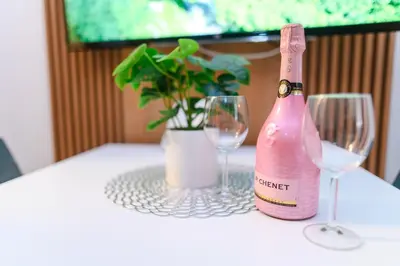 a pink bottle of wine sitting on a table with two glasses at BOŽUR apartmani, kod hotela Sunce in Soko Banja