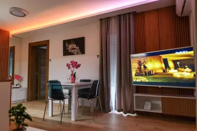 a living room with a dining table and a tv at BOŽUR apartmani, kod hotela Sunce in Soko Banja