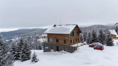a wooden house in the snow with a red car at NOOK Kopaonik Luxury Apart & House in Kopaonik