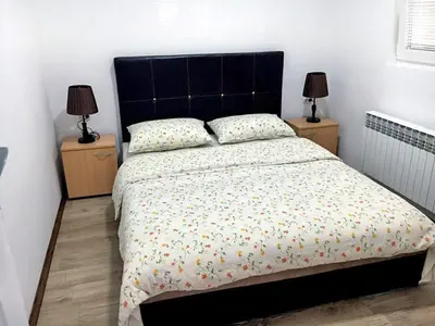 a bedroom with a large bed with two lamps on tables at Apartmani Vučić in Soko Banja