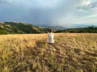 a woman sitting in a field of tall grass at Magia Vido Apartment-President Kop A109 in Kopaonik