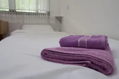a purple towel sitting on top of a white bed at Apartmani 
