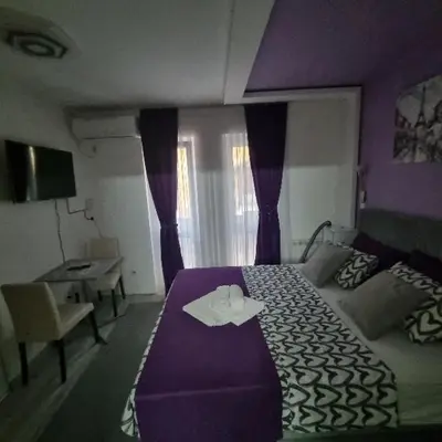 a hotel room with a purple bed and a desk at Studio Sestica vila Lenka2 in Vrnjačka Banja