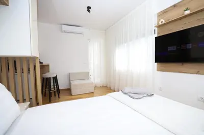 a white bedroom with a bed and a tv at Apartman Aleksandra Vrnjacka Banja in Vrnjci