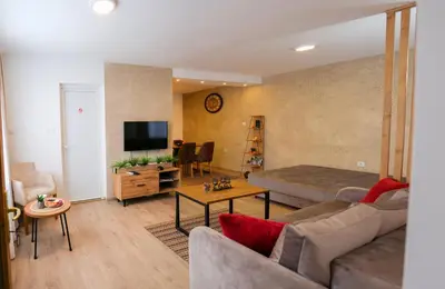a living room with a couch and a bed and a television at Apartman Jež in Kuršumlija
